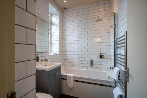 a bathroom with a tub and a sink and a toilet at The Bull Inn in Mildenhall