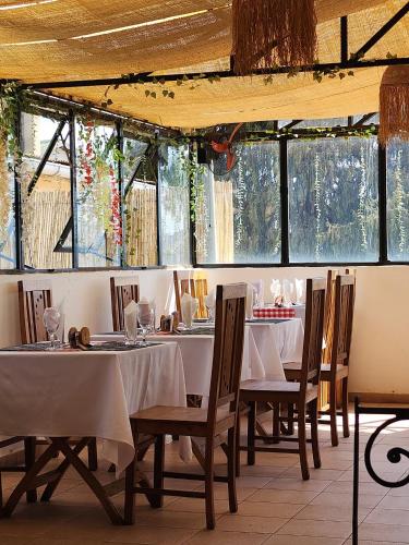 a dining room with tables and chairs and windows at La Casa Di Luna - Hotel with Pool and Restaurant in Antananarivo in Antananarivo