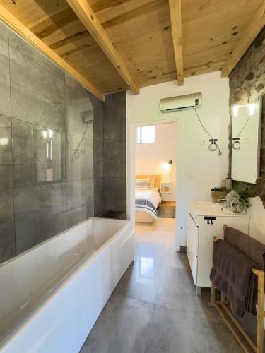 a bathroom with a bath tub and a bedroom at O Celeiro in Vale da Vide