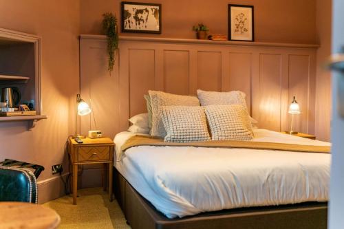 a bedroom with a bed with white sheets and pillows at The Bull Inn in Mildenhall