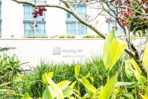 a building with windows and plants in front of it at Holiday Inn Mauritius Mon Trésor by IHG in Blue Bay