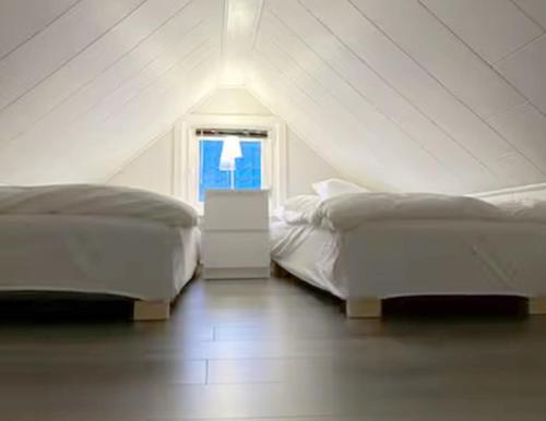 Dos camas en una habitación blanca con ventana. en Charming farmhouse in central Laholm, en Laholm