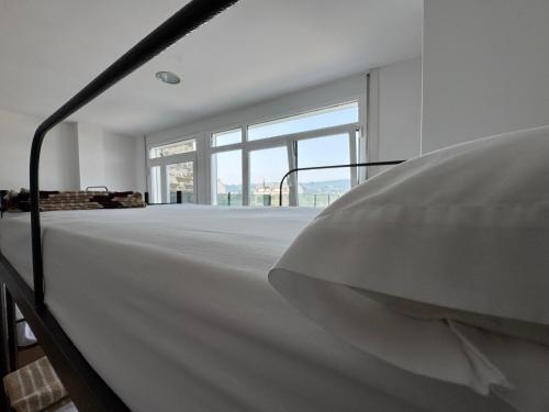 a white room with a bed and large windows at Albergue Internacional in Sarria