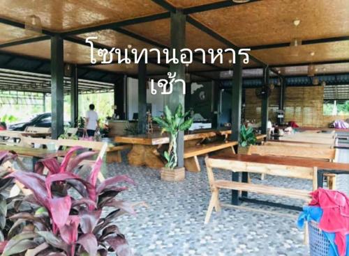a restaurant with wooden tables and potted plants at มาตาบุรี ริเวอร์เเควรีสอร์ท in Ban Gaeng Cho