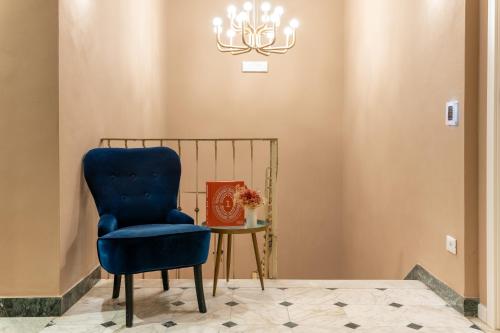 a blue chair sitting next to a table with a chandelier at Piccolo Hotel Puccini in Lucca