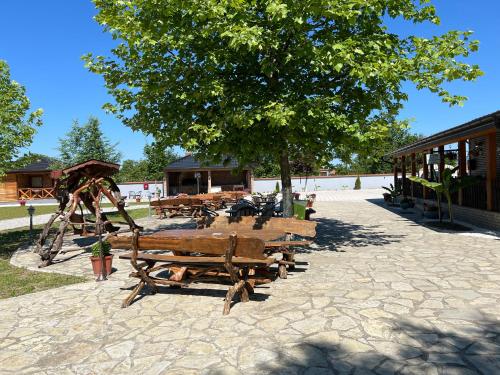a group of wooden benches sitting under a tree at Eko farma Kladovo in Kladovo