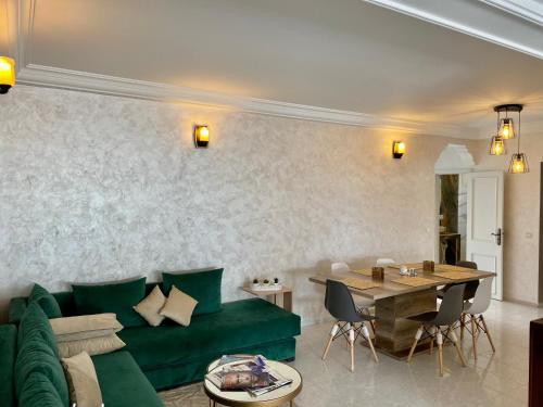 Una sala de estar con un sofá verde y una mesa. en Bel appartement avec une belle vue sur la grande mosquée Hassan II et la mer, en Casablanca