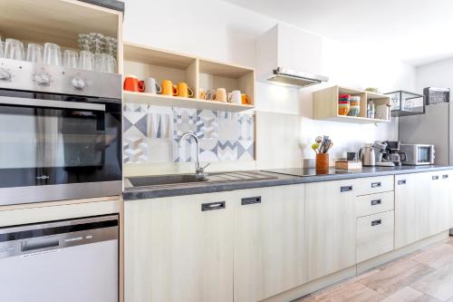a kitchen with white cabinets and a sink at Gîte Milena - SPA - Puy duFou - Grande capacité in Les Épesses