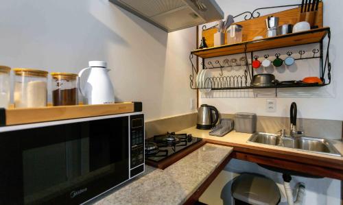 a kitchen with a microwave and a stove top oven at Contêiner 10 Hospedagem in Serra