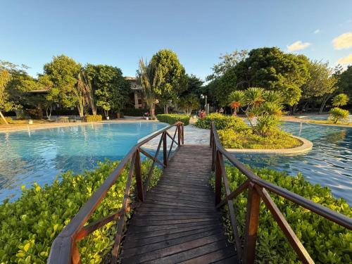 a wooden bridge over a pond in a park at Iloa resort AP luxo in Barra de São Miguel