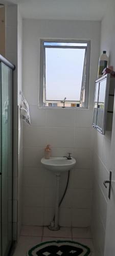 a white bathroom with a sink and a window at Aconchego in Marituba