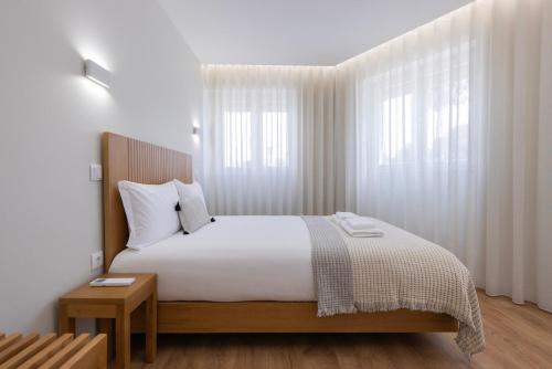 a bedroom with a bed with white sheets and a window at Modern 2BR Apt with Patio and AC in Lisbon