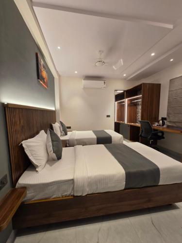 a hotel room with two beds and a desk at Hotel Skyview in Kondapur