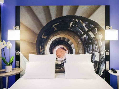 a bed in a room with a painting of a tunnel at Hotel De Bourbon Grand Hotel Mercure Bourges in Bourges