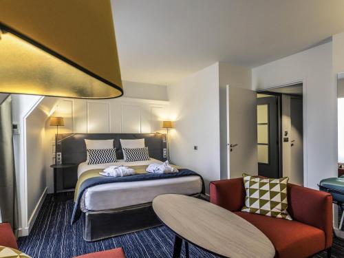 a hotel room with a bed and a chair at Hotel De Bourbon Grand Hotel Mercure Bourges in Bourges