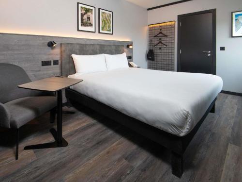 a bedroom with a large bed and a desk and a chair at ibis Styles London Gatwick Airport in Crawley