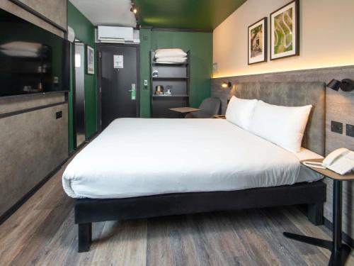 a bedroom with a bed and a desk with a telephone at ibis Styles London Gatwick Airport in Crawley