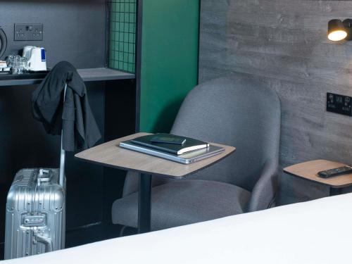 a table with a chair and a table with a book on it at ibis Styles London Gatwick Airport in Crawley
