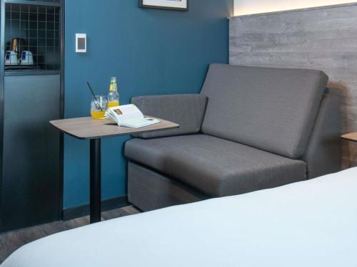 a room with a couch and a table with a book at ibis Styles London Gatwick Airport in Crawley
