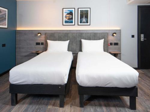 two beds with white sheets in a room at ibis Styles London Gatwick Airport in Crawley