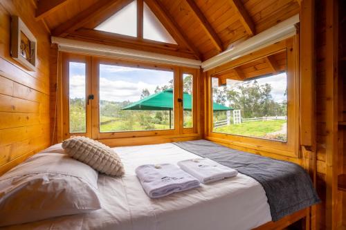 a bed in a wooden room with a large window at Cabaña de Pino Escapada Natural a 7 Min in Chiquinquirá