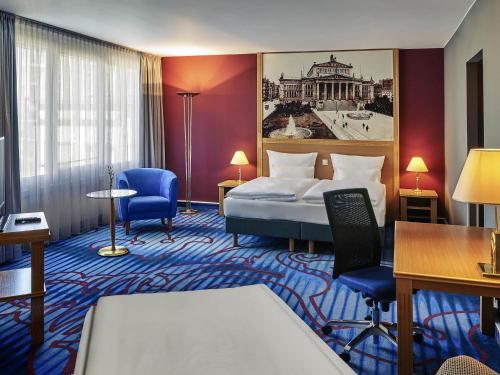 a hotel room with a bed and a table and chairs at Mercure Hotel Berlin Tempelhof in Berlin