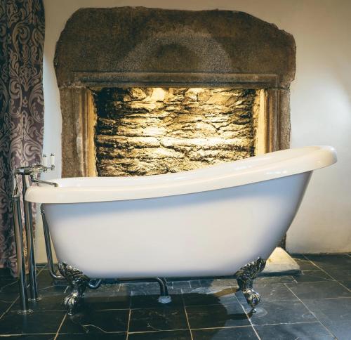 a white bath tub in front of a stone fireplace at Boringdon Hall Hotel and Spa in Plymouth