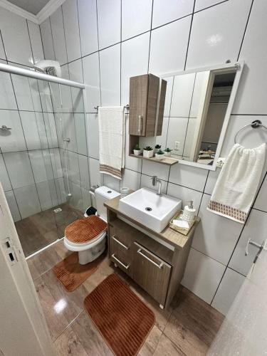 a bathroom with a toilet and a sink and a mirror at Della Giustina Residence Comforto Aparthotel - Aconchegante, Lindo, Moderno, Renovado entre Abba Pai Church e Centro in Criciúma