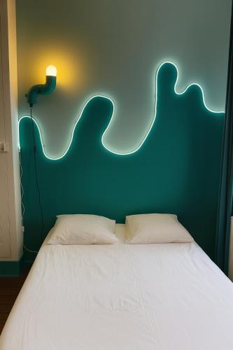 Una cama con un cabecero verde y una luz encima. en Chambre privée "turquoise" - Maison partagée, en Amiens