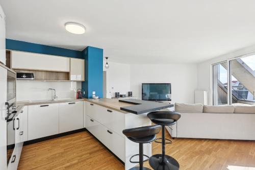 a kitchen with white cabinets and a blue accent wall at spacious and bright apartment in Bordeaux