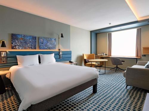 a hotel room with a large bed and a chair at Novotel Luxembourg Kirchberg in Luxembourg