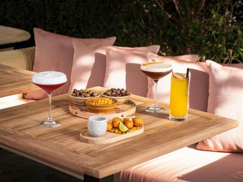 a wooden table with drinks and food on it at Novotel Luxembourg Kirchberg in Luxembourg