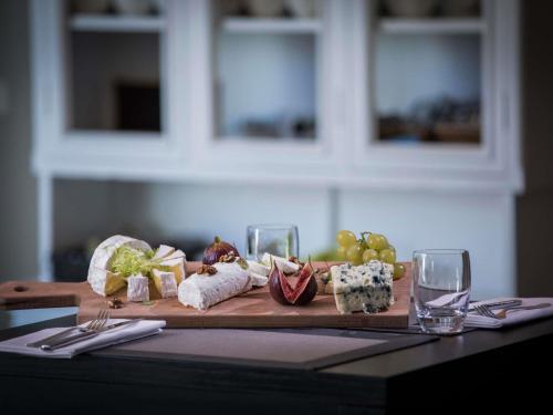a cutting board with different types of cheese and wine glasses at Novotel Luxembourg Kirchberg in Luxembourg