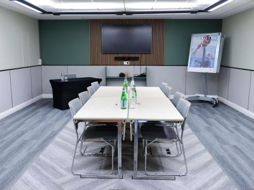 a conference room with a table and chairs and a flat screen tv at Novotel Luxembourg Kirchberg in Luxembourg