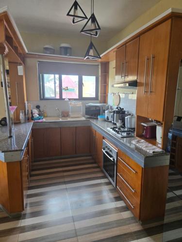 a large kitchen with wooden cabinets and a window at Chambre et SDB privées in Flic-en-Flac