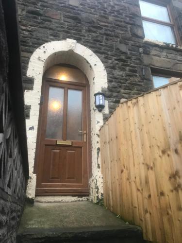 a wooden door in a stone building with a wooden fence at 54 - Room 3 - City views in Swansea