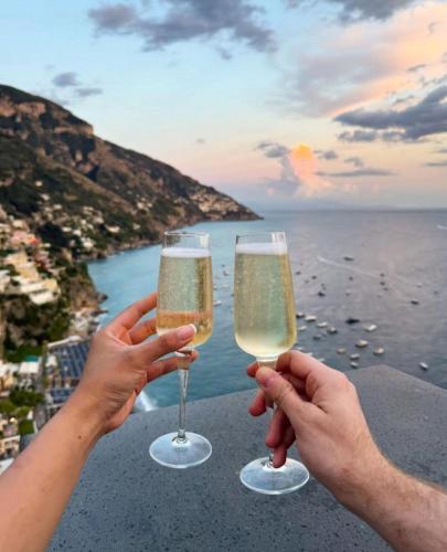 two people holding champagne glasses in front of the ocean at Hotel Casa Albertina in Positano