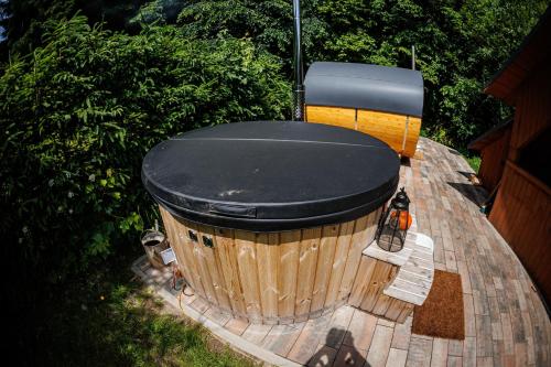 a wooden tub with a black top sitting next to two benches at Chata 70 Dřevěnka Prkenný Důl, Žacléř, Krkonoše in Žacléř