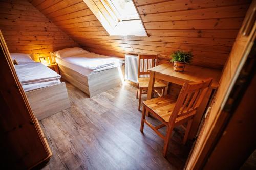 an attic room with a table and a bed and a window at Chata 70 Dřevěnka Prkenný Důl, Žacléř, Krkonoše in Žacléř