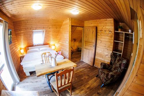 a bedroom in a wooden cabin with a bed and a table at Chata 70 Dřevěnka Prkenný Důl, Žacléř, Krkonoše in Žacléř