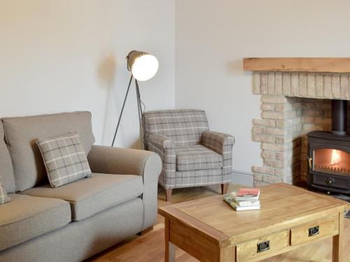 a living room with a couch and a chair and a fireplace at The School House in New Luce