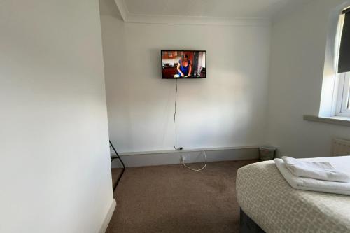 a room with a tv on a wall with a bed at Private Rooms with Shared Bathroom Bus Stop 8 Mins Away in Earley