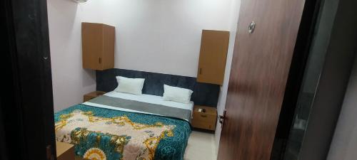 a small bedroom with a bed and a wooden door at Hotel swastik Inn in Ujjain