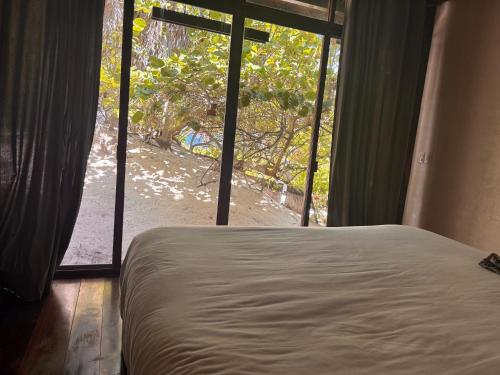 a bedroom with a bed and a large window at Libelula Tulum Beachfront Hotel in Tulum