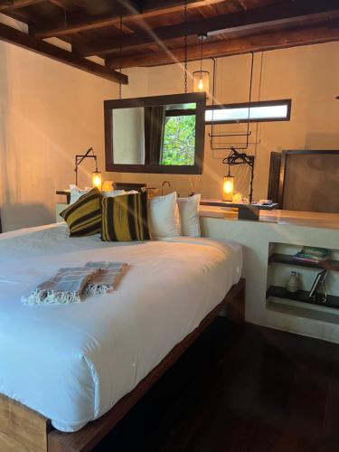 a bedroom with a large white bed with a mirror at Libelula Tulum Beachfront Hotel in Tulum