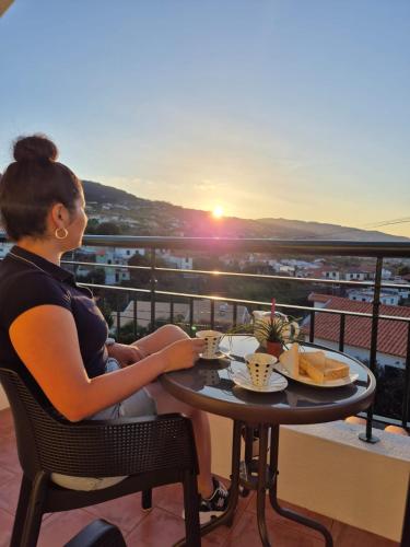 a woman sitting at a table with a cup of coffee at Panoramic Attic by Sabugo House in Relógio do Poiso