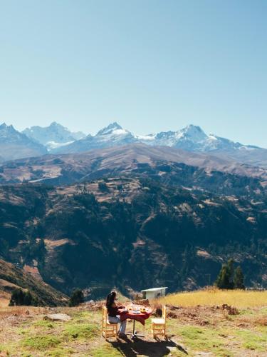 a person sitting at a table on top of a mountain at Mirador Willcacocha lodge - Glamping - Camping in Huaraz