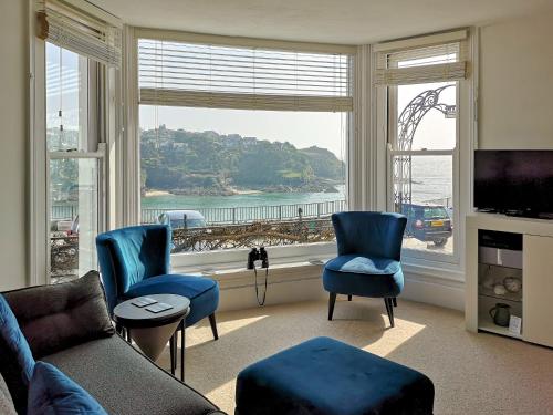 a living room with blue chairs and a large window at Seascape - St Catherine's Court in Fowey