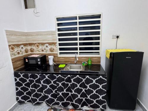 a small kitchen with a sink and a refrigerator at Cozy 4BR Homestay with 2 Baths Taman Seraya in Kulim