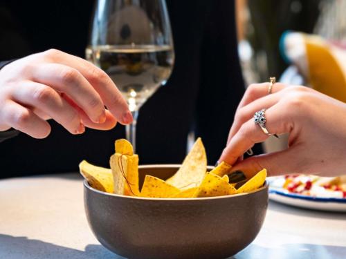 a person is preparing a bowl of nacho chips at Novotel Luxembourg Kirchberg in Luxembourg